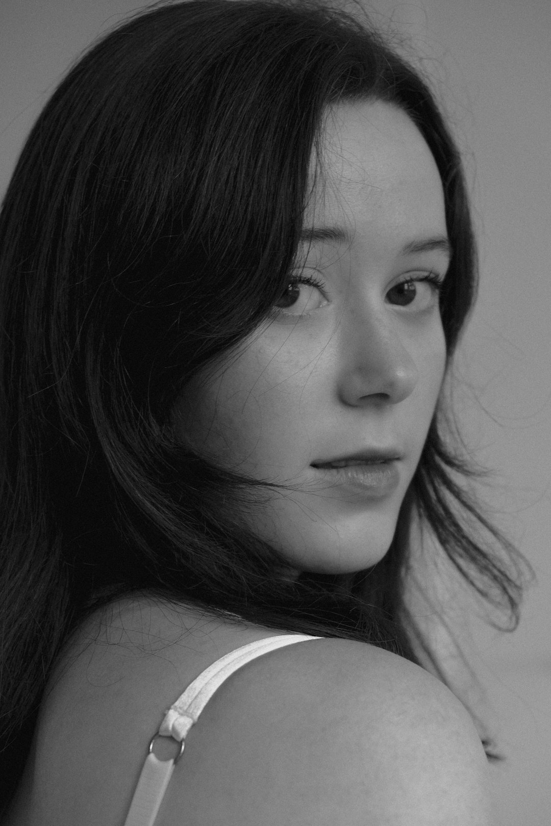 Editorial black and white portrait of a woman looking away from camera in soft studio light